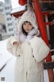 A woman in a white coat and hat standing in the snow.