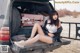 A woman sitting in the back of a truck with luggage.