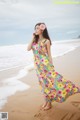 A woman in a colorful dress standing on a beach.