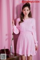 a woman in a pink dress standing next to a table