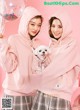 A couple of girls in pink hoodies holding a small dog.