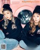 A couple of girls sitting next to each other in front of a washing machine.