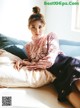 A woman sitting on top of a bed next to a pillow.