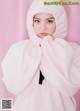 A woman in a pink hooded sweatshirt is posing for a picture.