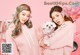 two girls in pink outfits holding a small white dog