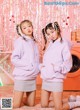 two girls in pink hoodies posing for a photo in front of a washing machine