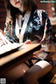 A woman in a black and white kimono sitting at a table.