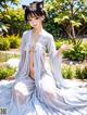 A woman in a white kimono sitting in a garden.