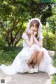 A woman in a white dress sitting on the ground.