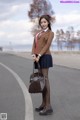 A woman in a school uniform is holding a brown bag.