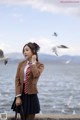 A woman in a school uniform standing by the water.