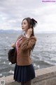 A woman in a school uniform standing by the water.