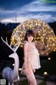 A woman in lingerie standing next to a white deer.