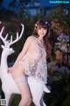 A woman in a white lingerie posing next to a white deer.