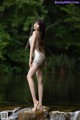 A woman in a silver dress standing on a rock in the water.