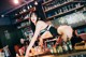 A woman in lingerie leaning over a bar counter.