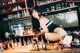 A woman sitting on top of a bar next to a counter.