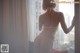 A woman in a white lingerie looking out a window.