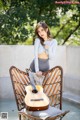 A woman sitting on a chair holding a guitar.