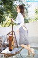 A woman in a gray dress holding a guitar.