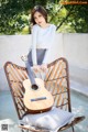 A woman sitting on a chair holding a guitar.