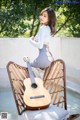 A woman sitting on a chair with a guitar.