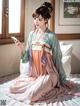 A woman in a kimono sitting on a bed holding a cell phone.