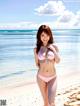 A woman in a pink bikini standing on a beach.