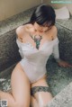 A woman sitting in a bathtub with a tattoo on her chest.