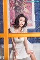 A woman in a white dress posing in front of a mirror.