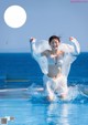 A woman in a white bikini is splashing in the water.