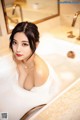 A woman in a bathtub with bubbles in it.