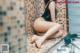 A woman in a black bathing suit sitting on a bathroom counter.