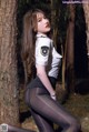 A woman in a police uniform posing in the woods.