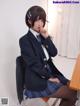 A woman in a school uniform sitting at a desk.