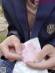 A person in a school uniform holding a pink envelope.