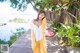 A woman in a yellow and white pajamas posing by a pool.