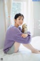 A woman sitting on a bed holding a stuffed animal.