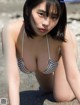 A woman in a striped bikini sitting on the beach.