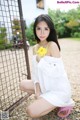 A woman in a white dress holding a yellow flower.