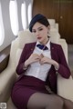 A woman in a uniform sitting on a chair in an airplane.