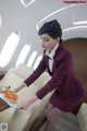 A woman in a purple uniform holding a plate of food.