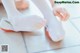 A woman putting on a pair of white ballet shoes.