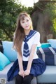 A woman in a school uniform sitting on a couch.