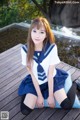 A woman in a school uniform sitting on a wooden dock.