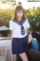 A woman in a sailor outfit sitting on a chair.