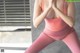 A woman in a pink sports bra top and pink leggings doing yoga.