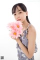 A woman holding a bunch of pink flowers in her hand.