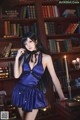 A woman in a blue lingerie posing in front of a bookshelf.