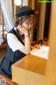 A woman sitting at a table with a book and a hat.